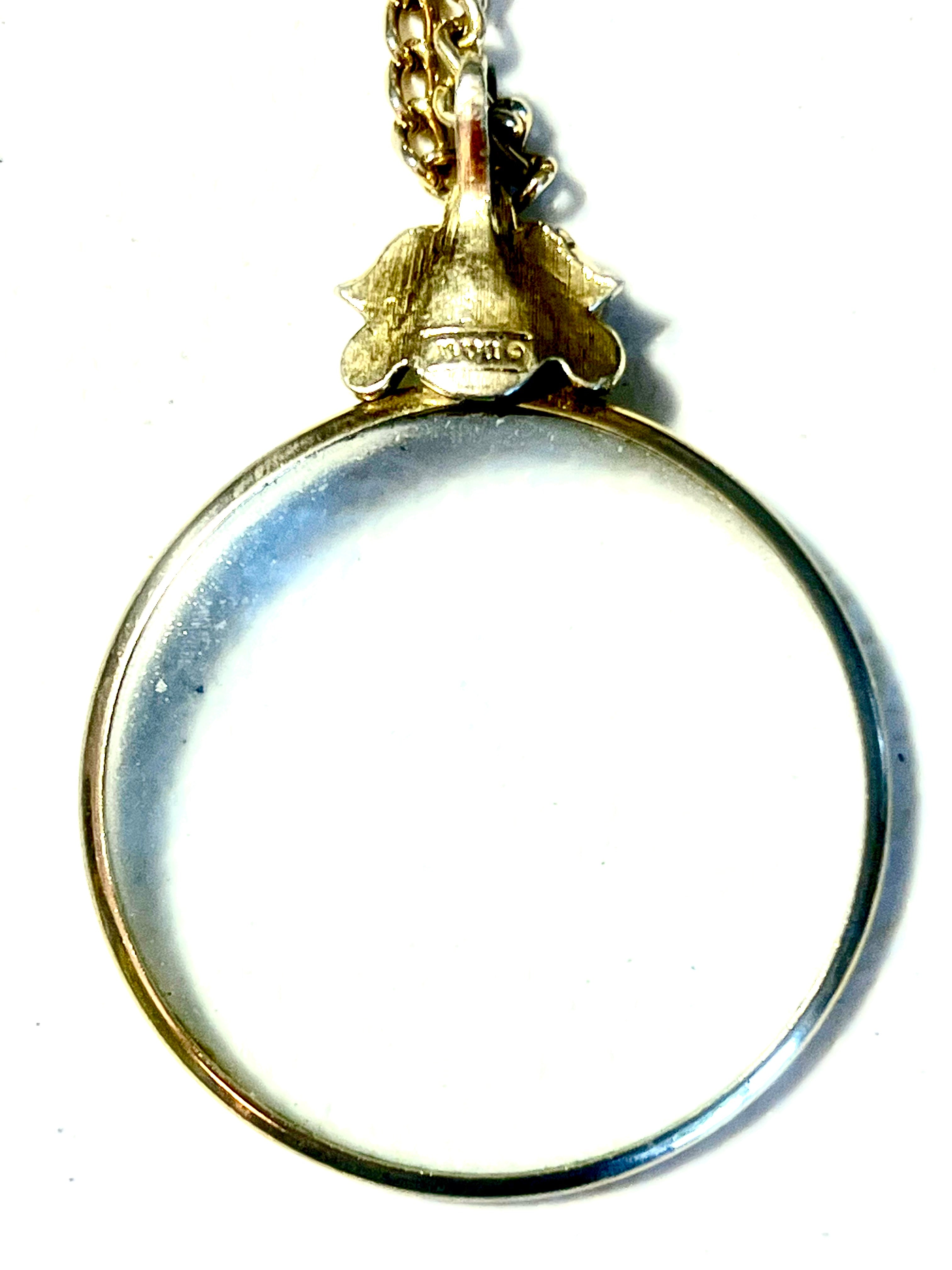 Vintage 1976 Avon magnifying glass pendant necklace with Fleur de Lis design and 28 inch serpentine gold tone chain.